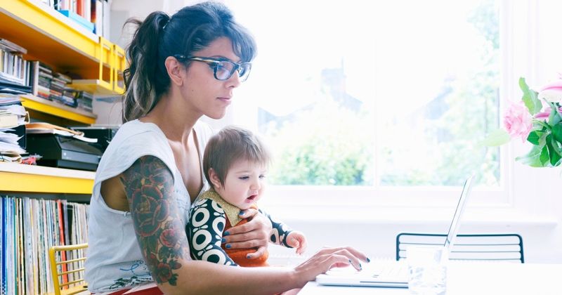 Une mère célibataire travaille sur son ordinateur sous le regard de son tout-petit.