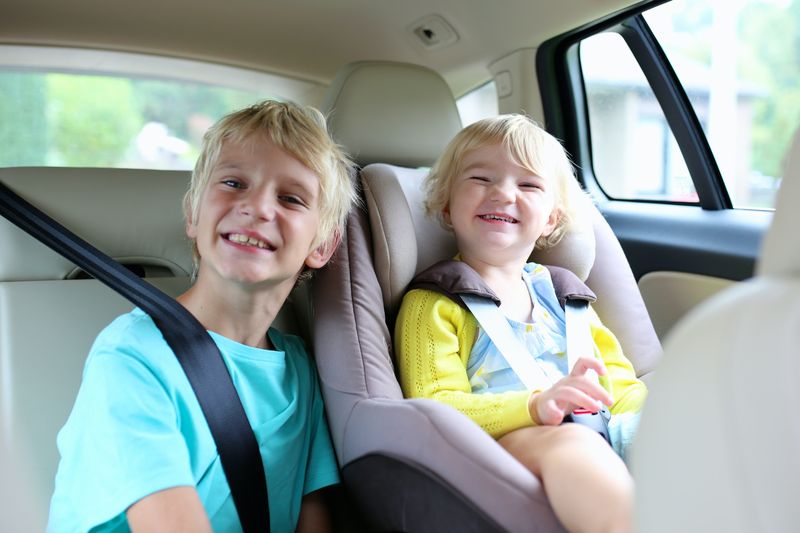 Enfants heureux, adorable petite fille avec un frère adolescent assis ensemble dans une voiture moderne verrouillée avec s...