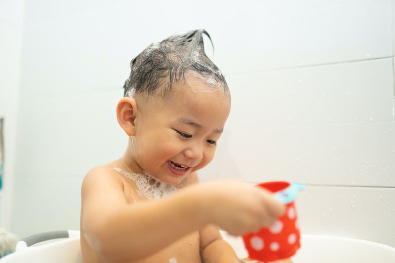 bébé asiatique souriant enfant garçon joue avec un jouet dans la baignoire dans la salle de bain, mignon petit garçon asiatique avec drôle...