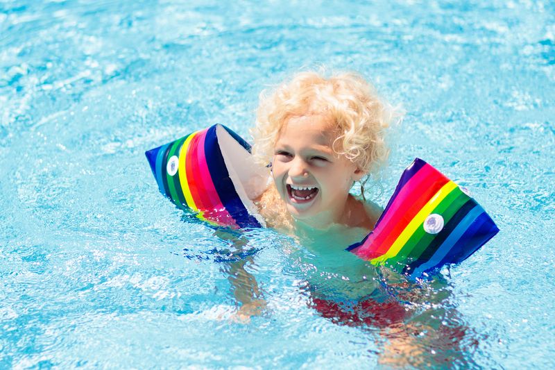 Enfant dans la piscine portant des brassards gonflables colorés. Les enfants apprennent à nager avec un flotteur. Flo...