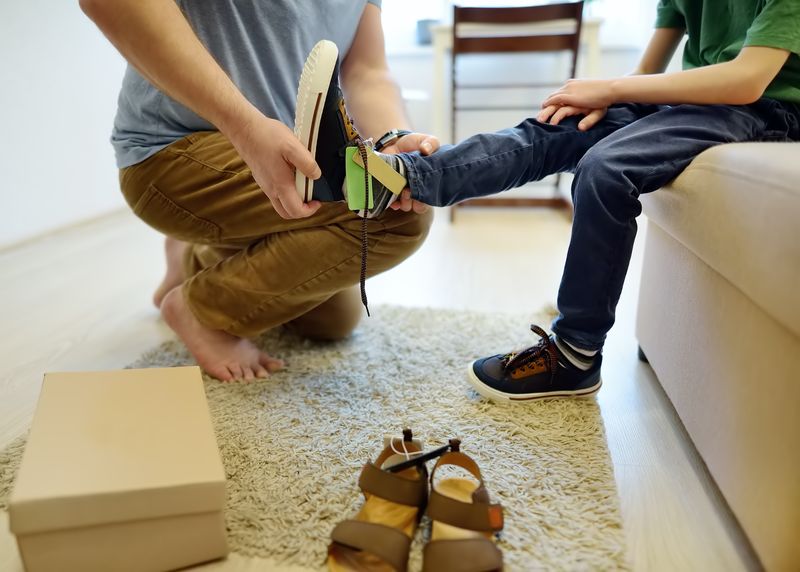Achats en ligne pour bébés et enfants. Père aidant à ajuster les chaussures de son enfant à la maison. Gratuitement...