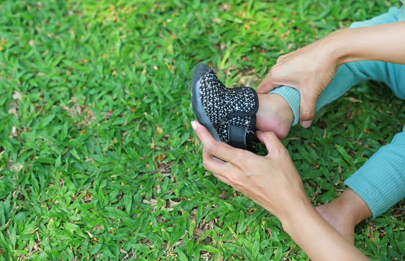 Mains de mère aidant son bébé à mettre des chaussures dans le jardin en plein air.