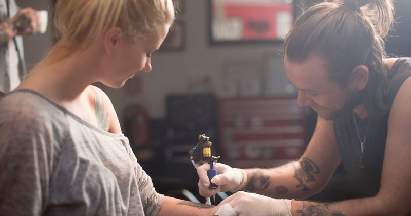 Femme se faisant tatouer - tatouages ​​​​de dinosaures.