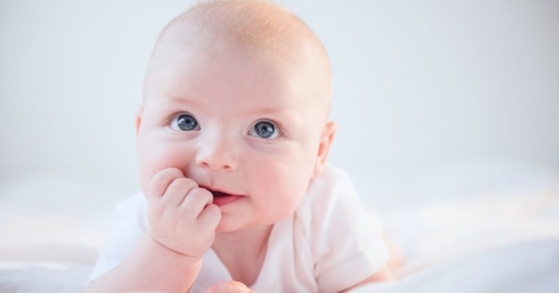 Un mignon bébé aux yeux bleus lève les yeux.